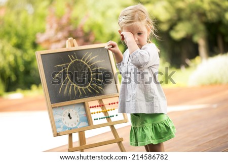 Young girl playing outside drawing on board