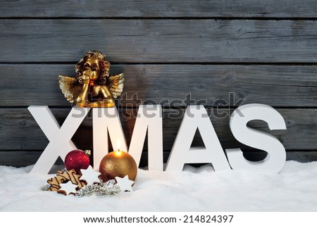Capital letters forming the word xmas golden putto figurine and christmas cookies on pile of snow against wooden wall