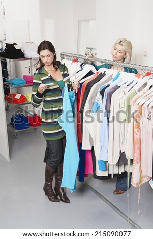 Two women in fashion store woman checking price tag
