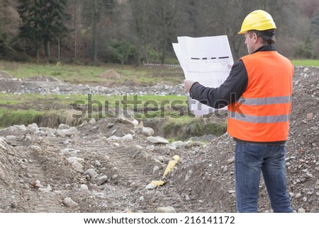 Architect is standing in a construction site looking in a construction plan