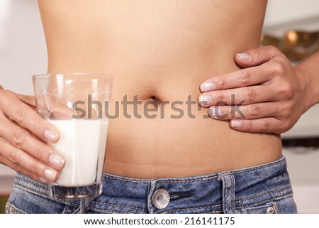 Holding glass of milk, one hand on stomach