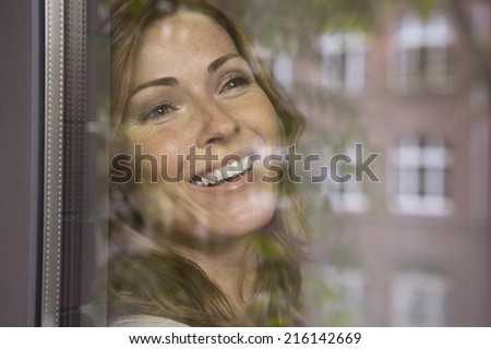 Germany, Woman looking out the window smiling