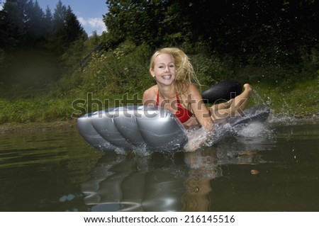 Austria, Salzburger Land, Lake Reitecksee, Young woman on airbed fooling around