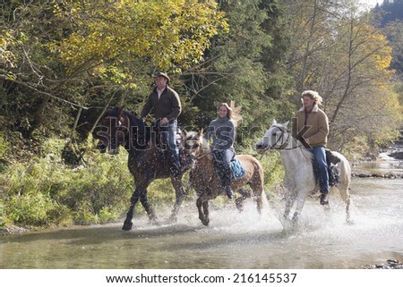 Austria, Salzburger Land, Altenmarkt, Young people riding horses across river