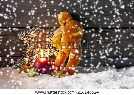 Gingerbread man on pile of snow against wooden wall