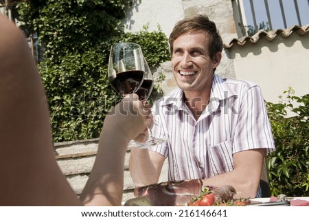 Italy South Tyrol couple in restaurant toasting with red wine smiling