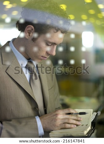 Young businessman standing behind glass pane