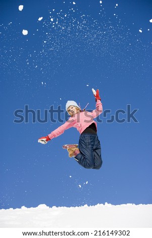 Austria, girl jumping in snow, low angle view