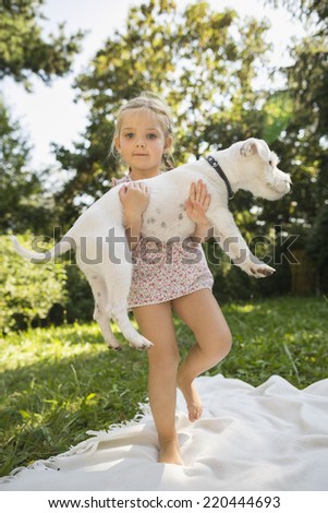 Young girl lifting up white jack russel in garden