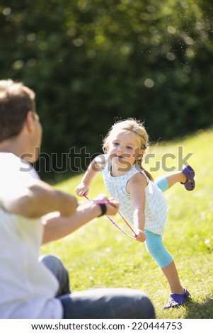 Father and daughter playing tug of war in garden