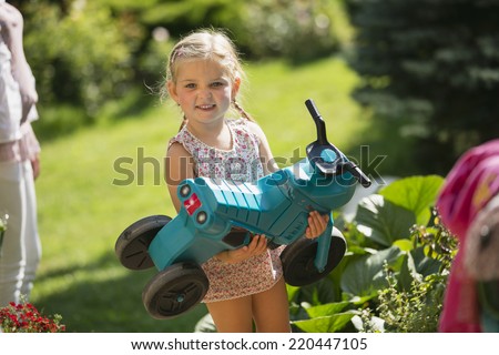 Young girl holding toy motorbike in garden