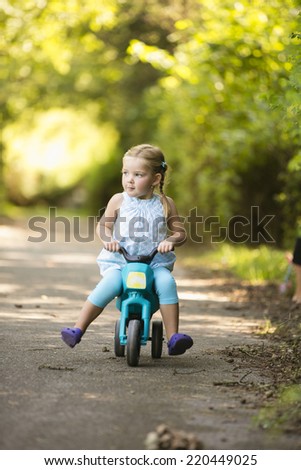 Young girl sitting on toy motorbike in park