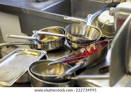 Kitchen in restaurant, sink filled with dirty metal dishes
