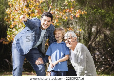 Boy in garden with grandfather and father, pointing