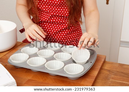 Woman baking muffins with cupcake liners and a muffing tin
