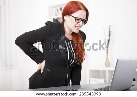 Young businesswoman with back pain in office