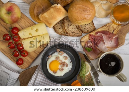 Fried egg with shrimps in pan, cheese, ham, bread and buns,coffee