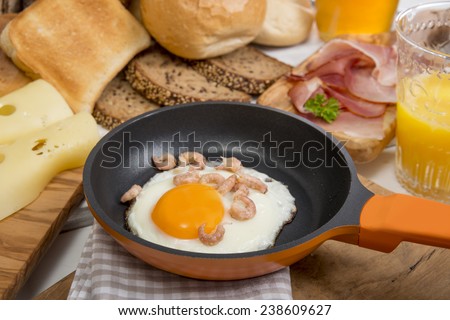 Fried egg with shrimps in pan, cheese, ham, bread and buns