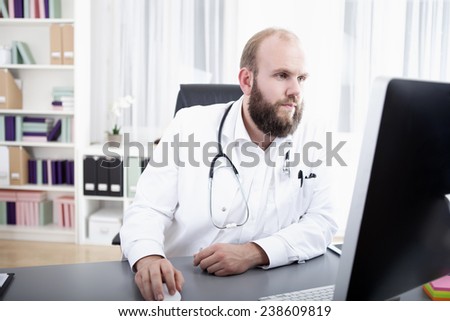 Doctor in practice sitting at desk working at computer