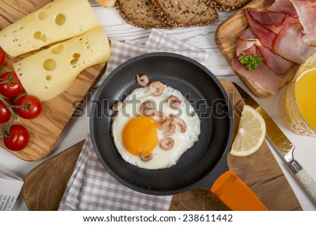 Fried egg with shrimps in pan, cheese, ham, bread and buns