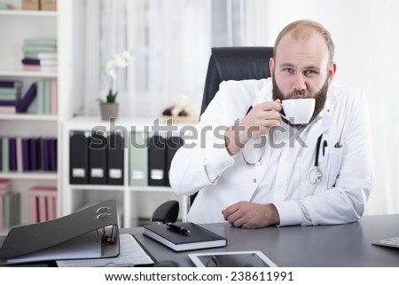 Doctor sitting at desk, drinking coffee