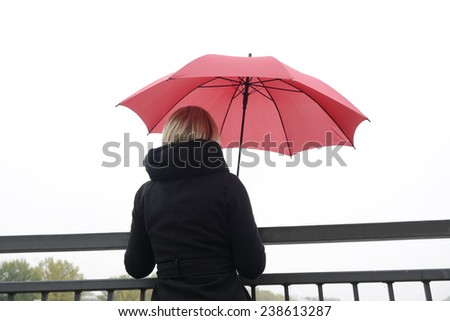 Young woman with red umbrella standing at railing,Berlin