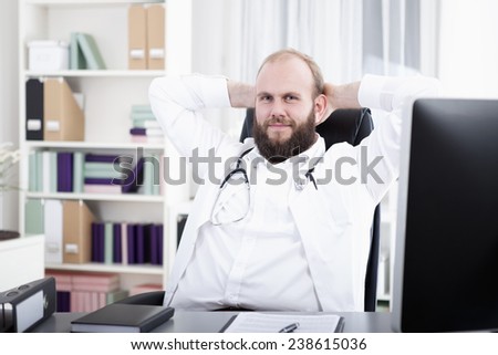 Doctor sitting relexed at desk, hands behind head