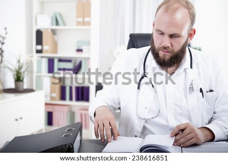 Doctor sitting at desk checking time planner