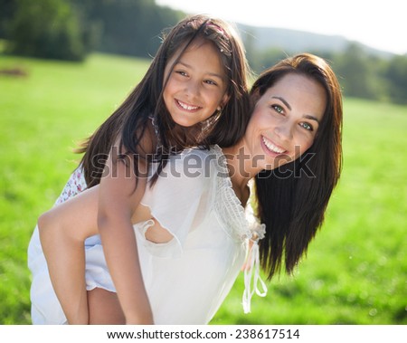 Mother carrying daughter piggyback, laughing