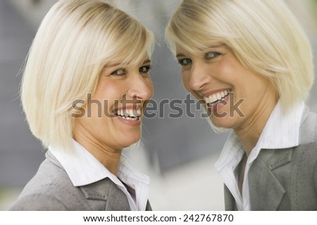 Germany, businesswoman looking at mirror image