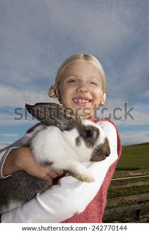 Girl holding rabbit in arms, portrait, close-up