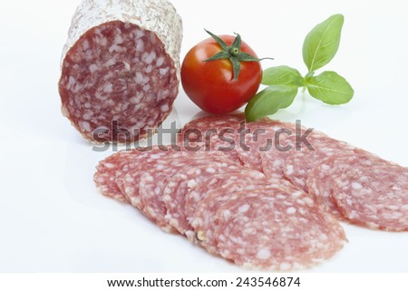 Salami slices and tomato on white background