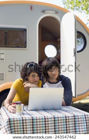Germany, Leipzig, Ammelshainer See, Young couple sitting by camping trailer using laptop