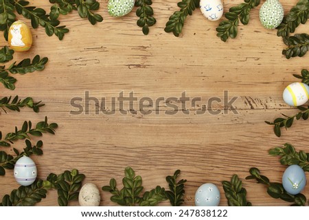 Twigs and easter eggs as frame on wood, copy space