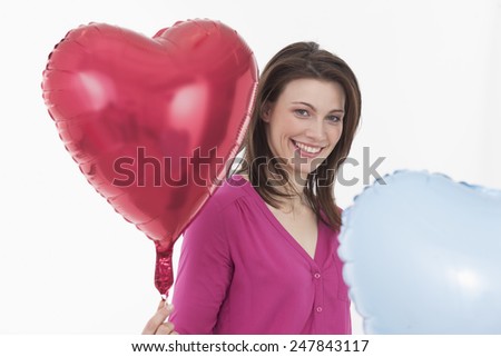 Young woman holding heart shaped balloons, portrait