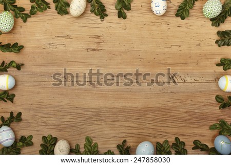 Twigs and easter eggs as frame on wood, copy space
