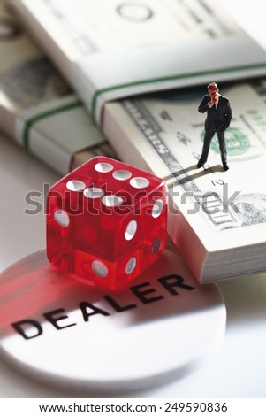 Manager figurine standing on bundle of 100 us dollar notes with dice