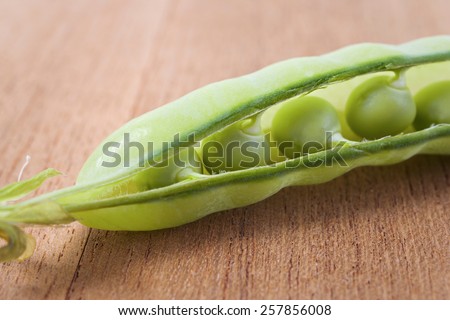 Pea pod slightly opened showing fresh peas