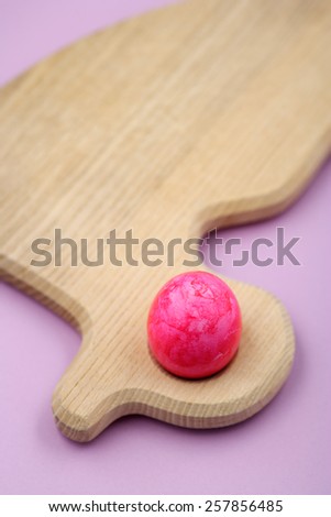 Pink easter egg on duck-shaped wooden breakfast board