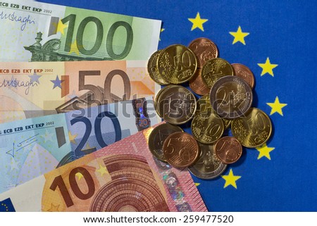 Euro notes and coins on EU flag