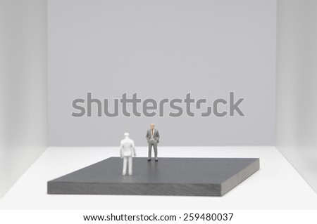 Two businessmen figurines standing face to face on platform.