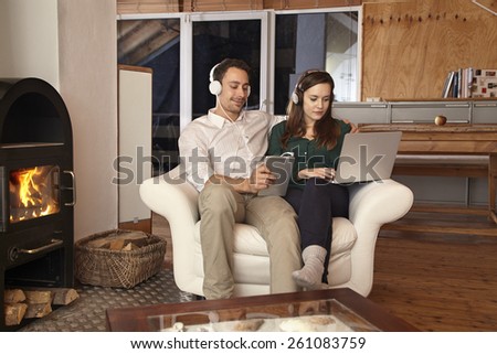 Couple using laptop and tablet listening to music