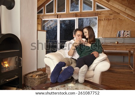 Couple sitting by fireplace and drinking tae