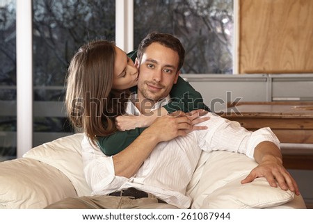Man sitting in armchair, woman embracing and kissing him