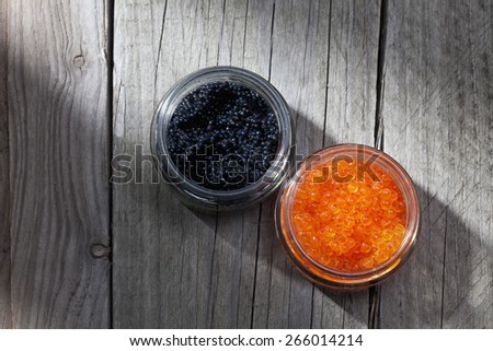Black and red caviar in glasses on wood