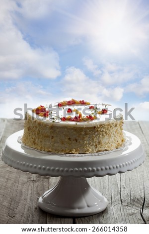 Wine cream cake on cake stand, on wood, sunshine
