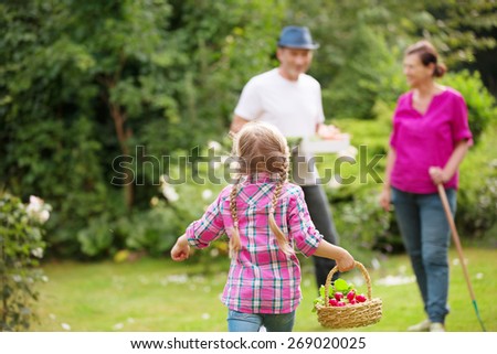 Family in garden, little girl running with basket in hand