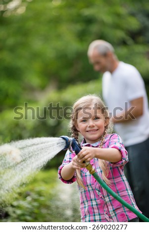 Father and daughter watering plants in garden