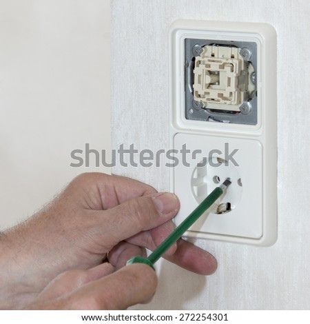 Renovation, hand with screwdriver, light switch and plug socket