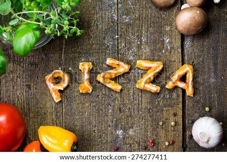 Vegetables and spices on wood, word Pizza